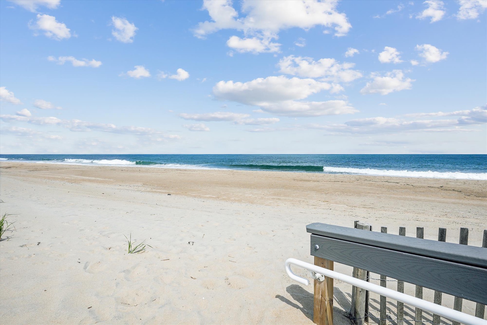 A pristine sandy beach stretches along turquoise waters under bright blue skies—a tranquil coastal setting near the property with gentle waves and expansive shoreline.