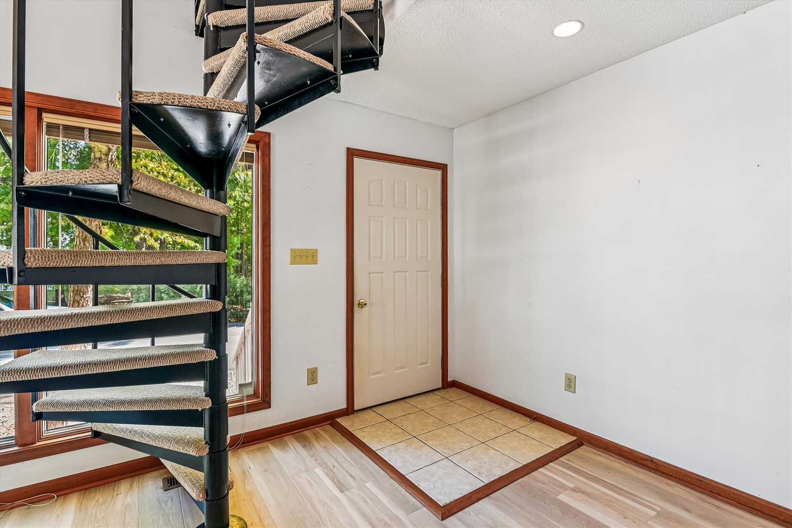 Step into your bright foyer where polished hardwood floors meet elegant tile, while the striking spiral staircase beckons you upstairs.