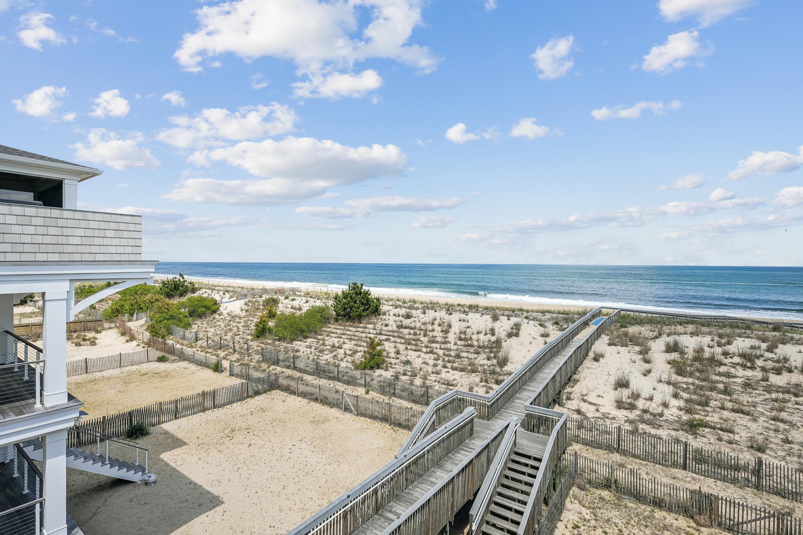 The property offers direct beach access with a private walkway leading over protected dunes to pristine oceanfront sand, framed by natural vegetation and protected coastal landscapes.