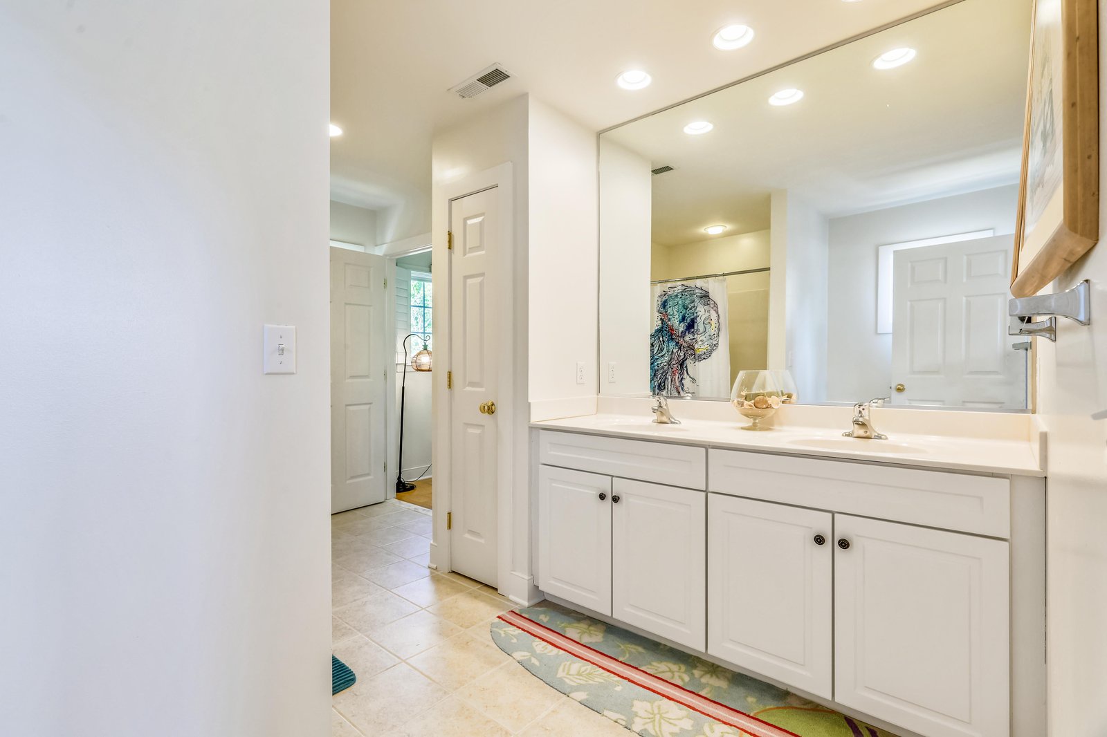 Your private bathroom features a bright vanity with dual sinks and plenty of storage, all bathed in soft recessed lighting for a calm, refreshing start to your day.