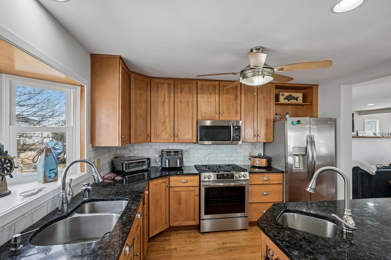 A fully equipped kitchen with stainless steel appliances, granite countertops, and warm wood cabinetry invites you to prepare meals while enjoying views through the waterside window.