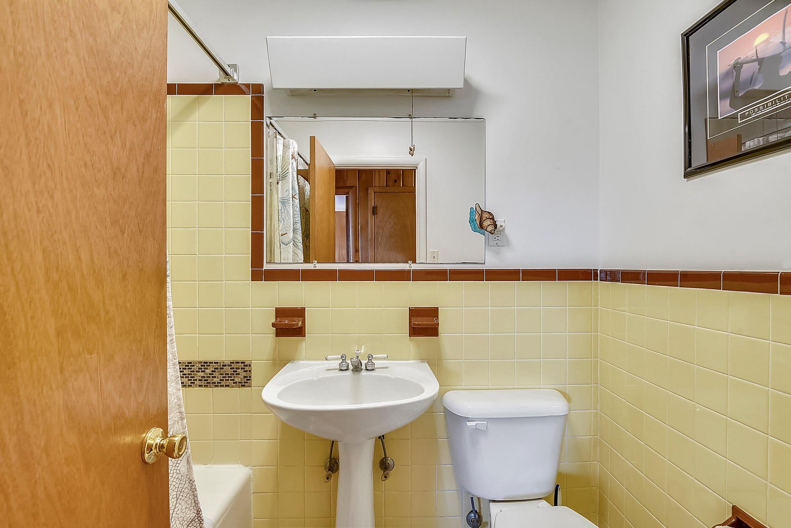 This charming retro bathroom features cheerful yellow and brown tile with classic fixtures, offering you a nostalgic touch of character and a warm, welcoming feel.