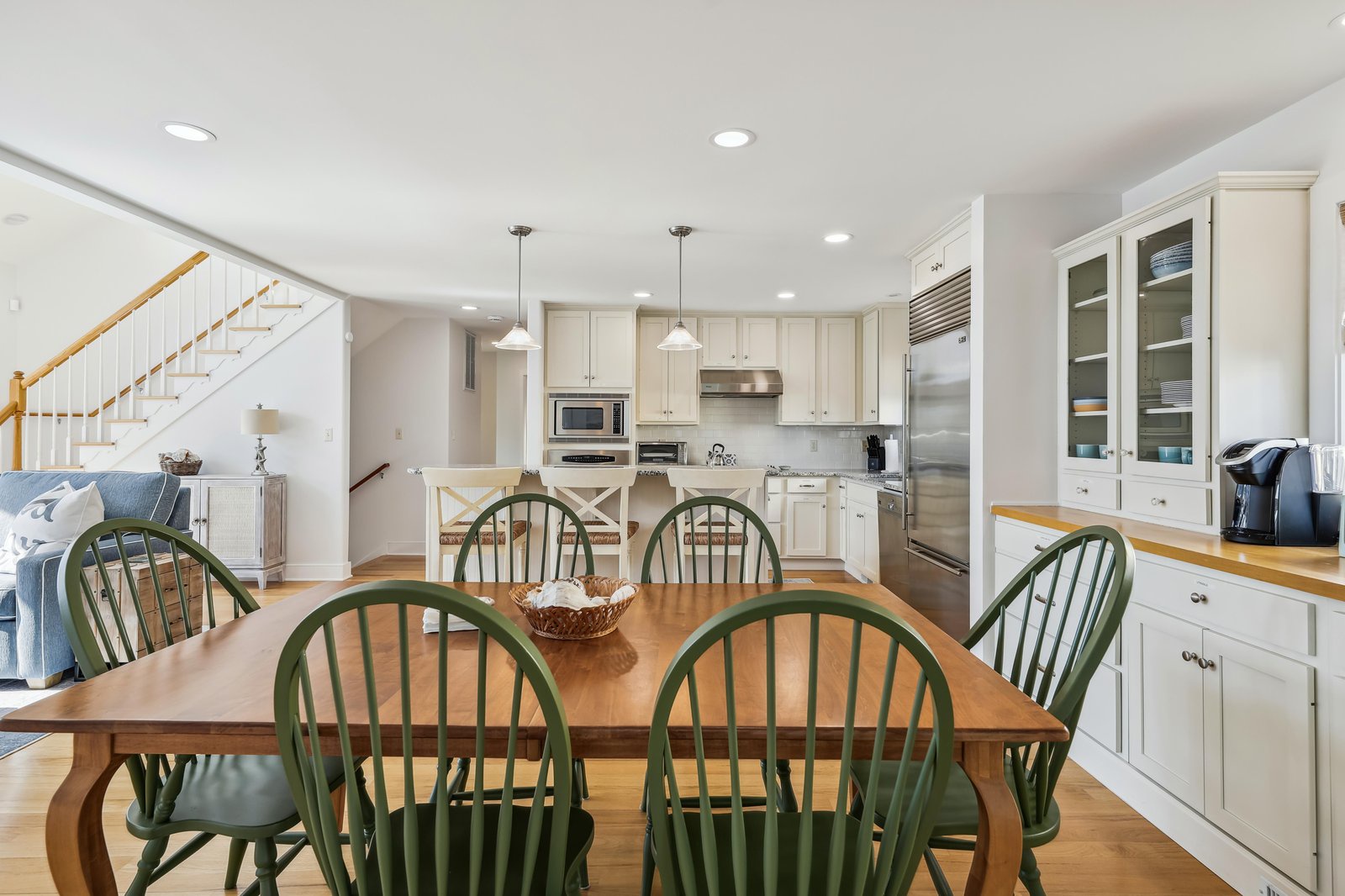 Gather around this spacious farmhouse kitchen and dining area, where bright white cabinetry, warm wood floors, and cozy seating invite you to cook, share meals, and relax together.