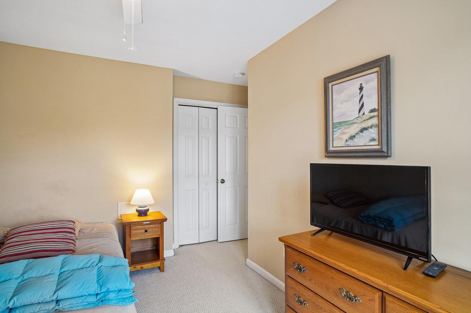 Your cozy bedroom features a comfy bed, convenient TV for evening entertainment, ample closet space, and coastal artwork that brings a peaceful, beachy vibe to your private retreat.