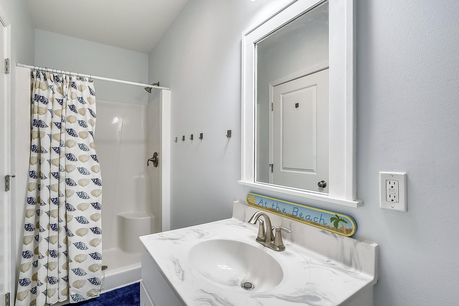 Step into your bright, coastal-themed bathroom with a pristine shower and vanity. Playful beach-inspired details invite you to unwind and refresh after a day exploring nearby shores.
