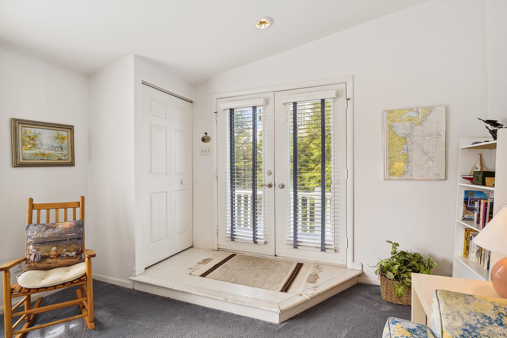 This bright, welcoming entrance area features charming local artwork and a cozy reading nook, setting the tone for your peaceful retreat with lovely natural light streaming through the French doors.