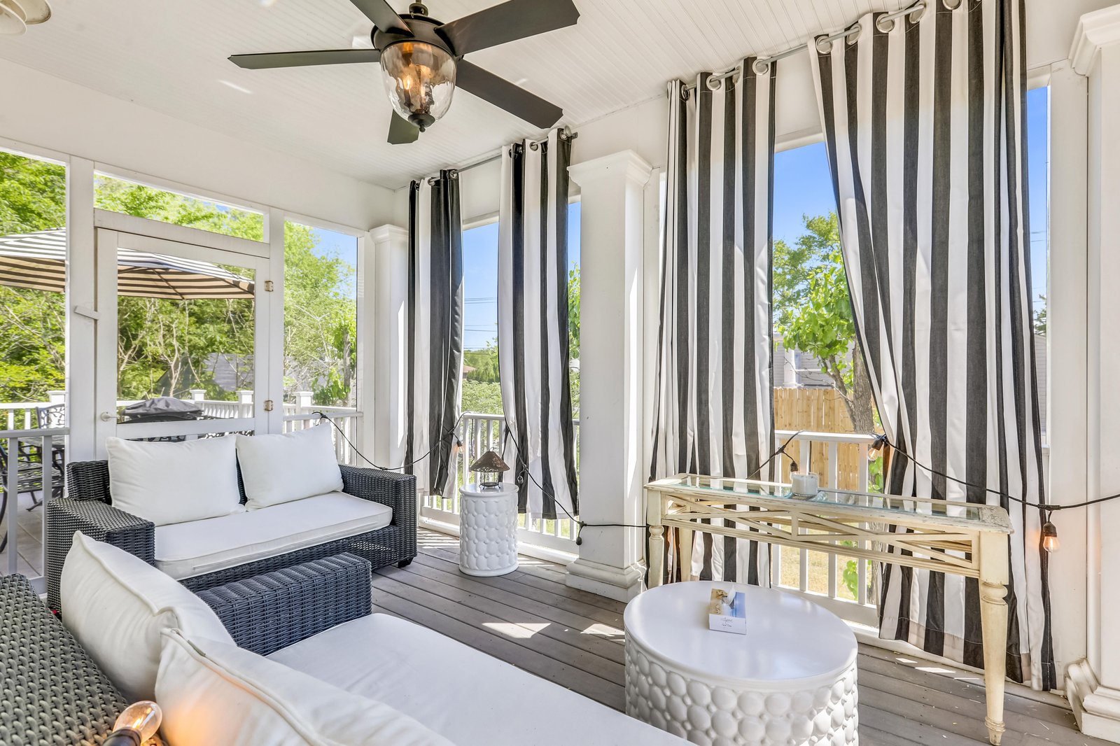 Settle into your private screened porch with plush seating and a gentle breeze overhead. Striped curtains frame peaceful views of the surrounding greenery, creating your perfect spot to unwind any time of day.