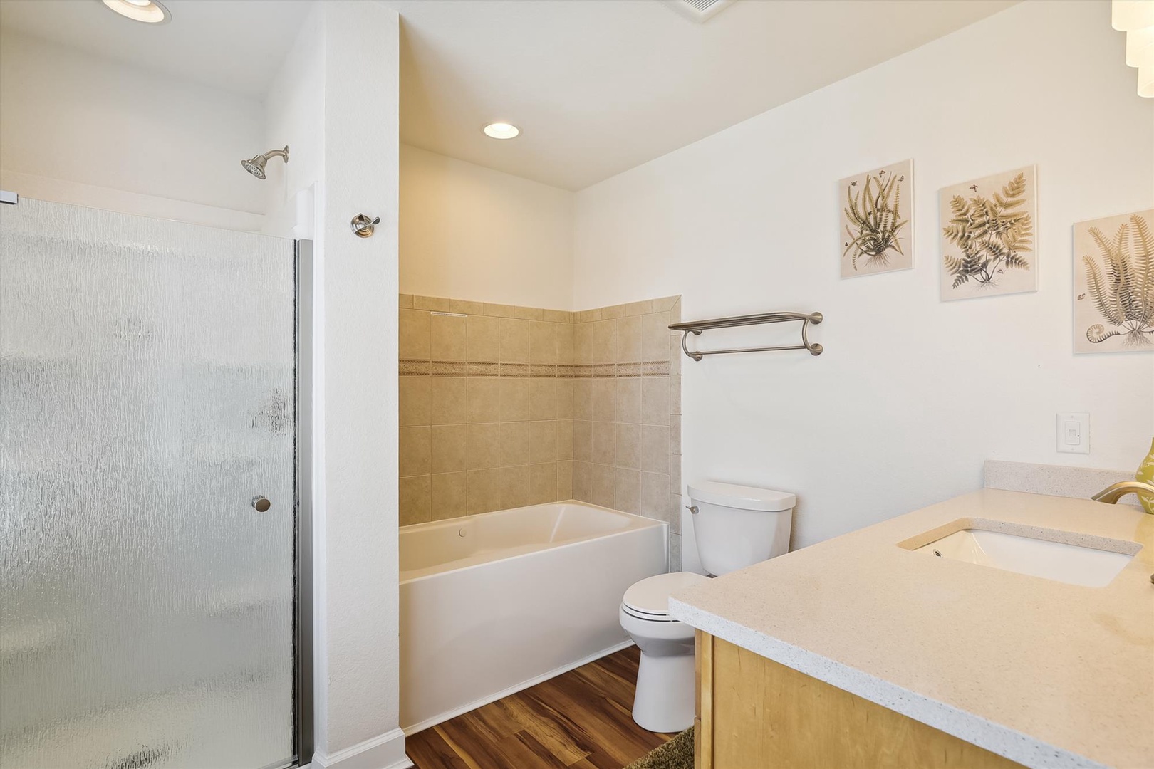 Refresh in your spacious bathroom with a walk-in shower and soaking tub, both framed by warm tile accents and botanical artwork that invite calm moments.