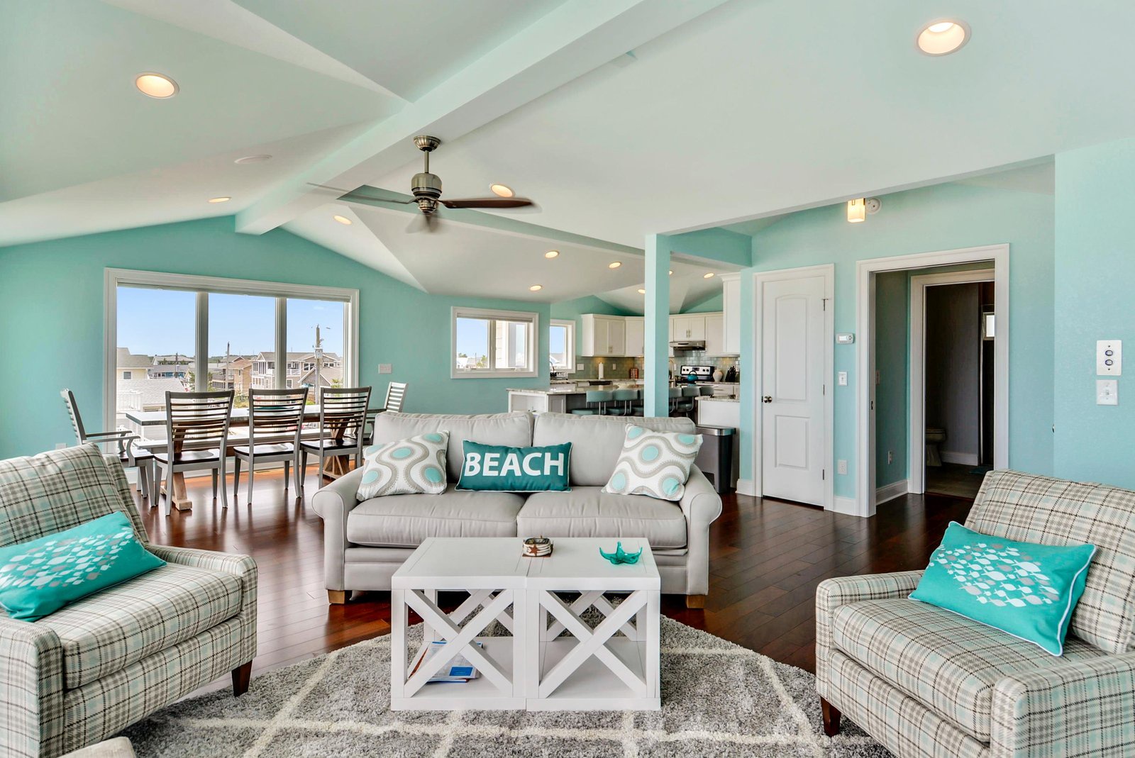 Step into your coastal haven where soft turquoise walls and soaring vaulted ceilings create an airy, beachside atmosphere perfect for relaxing after sun-soaked days.