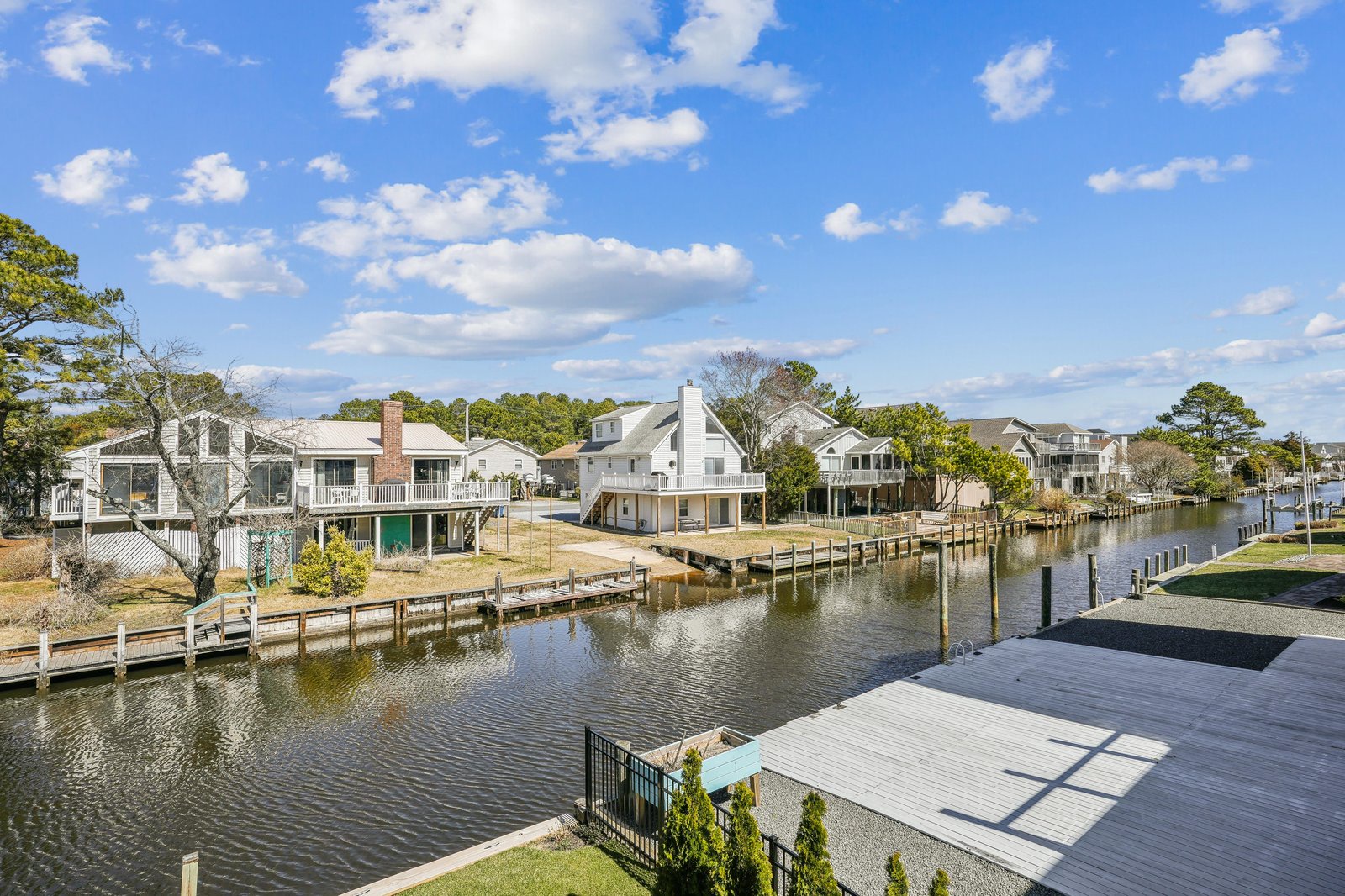 Waterfront vacation homes line a peaceful canal, with private docks extending into calm waters under clear blue skies.