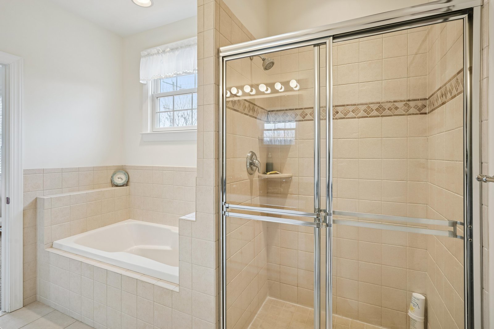 Step into your private spa-like retreat with a spacious walk-in shower and relaxing soaking tub, beautifully tiled in warm neutral tones with elegant accent detailing.