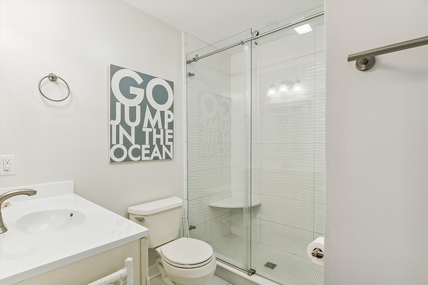 Step into a fresh, modern bathroom with a sleek glass shower and coastal charm. The playful wall art adds a touch of personality to your private retreat.
