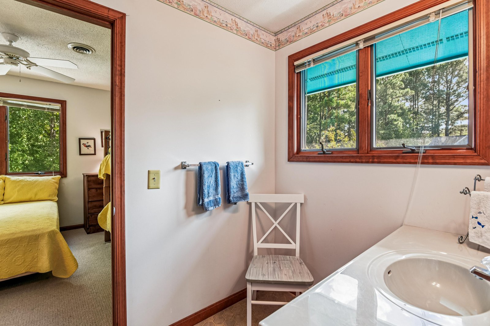 Step into your private ensuite, where natural light filters through the window and fresh towels await. The door to your cozy bedroom stands just steps away, making morning routines effortless.