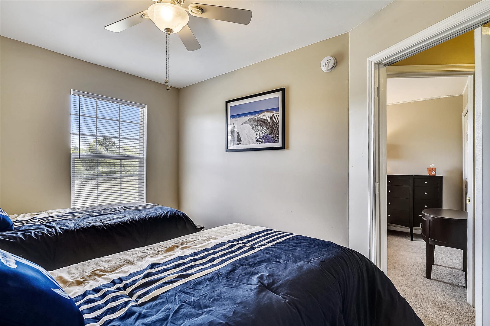 Your comfortable bedroom features two cozy beds, soft natural light, and a convenient ceiling fan. Relax after a day of adventure in this peaceful retreat.