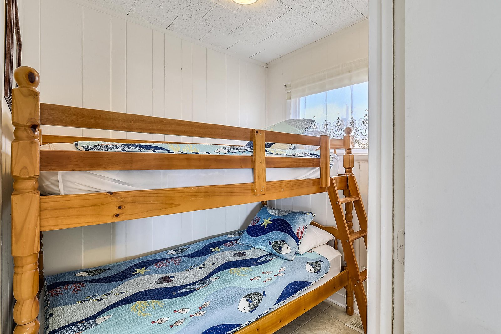 Cozy bunk beds perfect for your little ones, featuring charming ocean-themed bedding that sets the scene for sweet dreams.