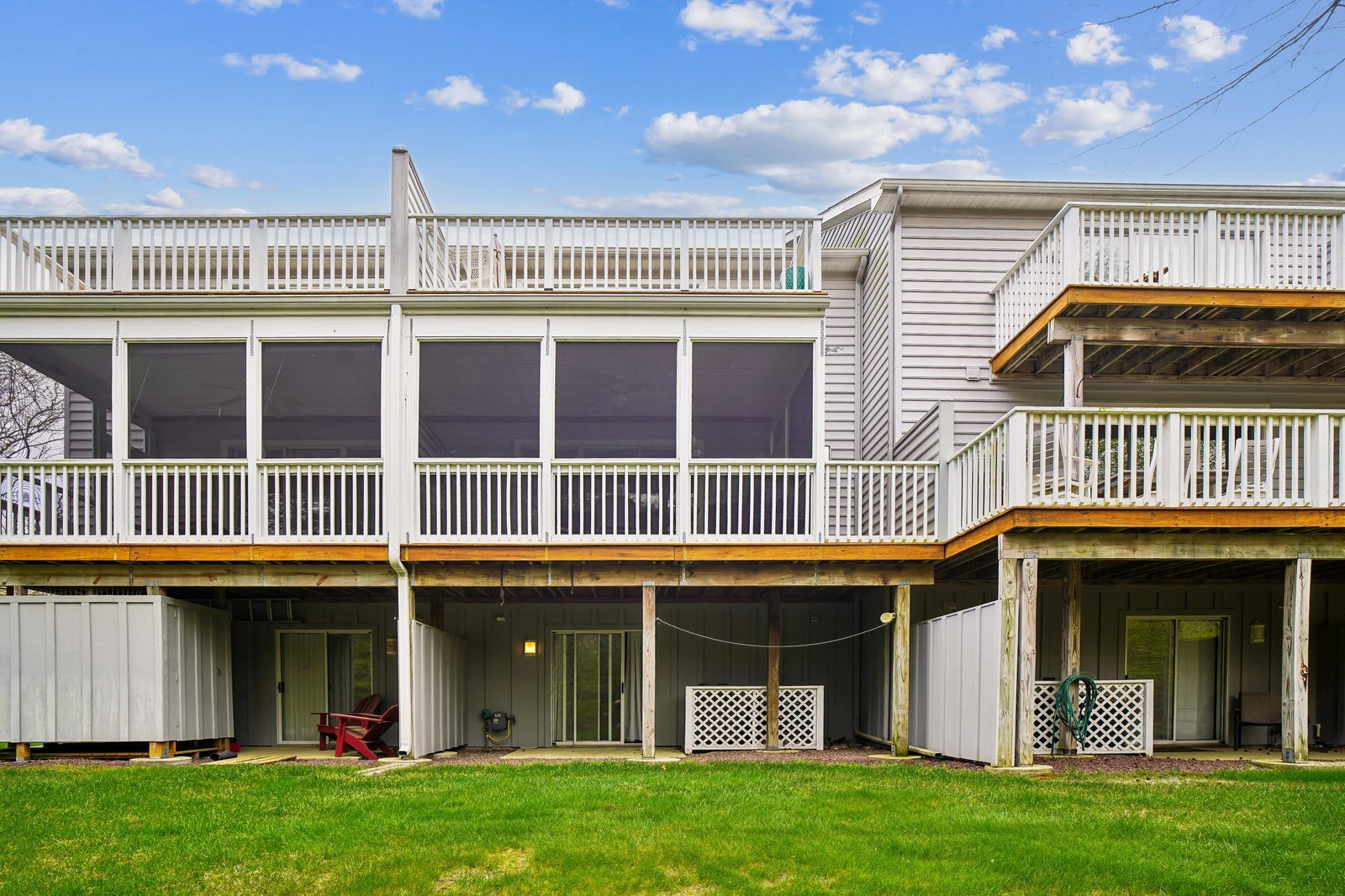 Multiple floors of covered porches and sunny decks overlook a spacious backyard, offering fresh air and outdoor relaxation throughout the property.