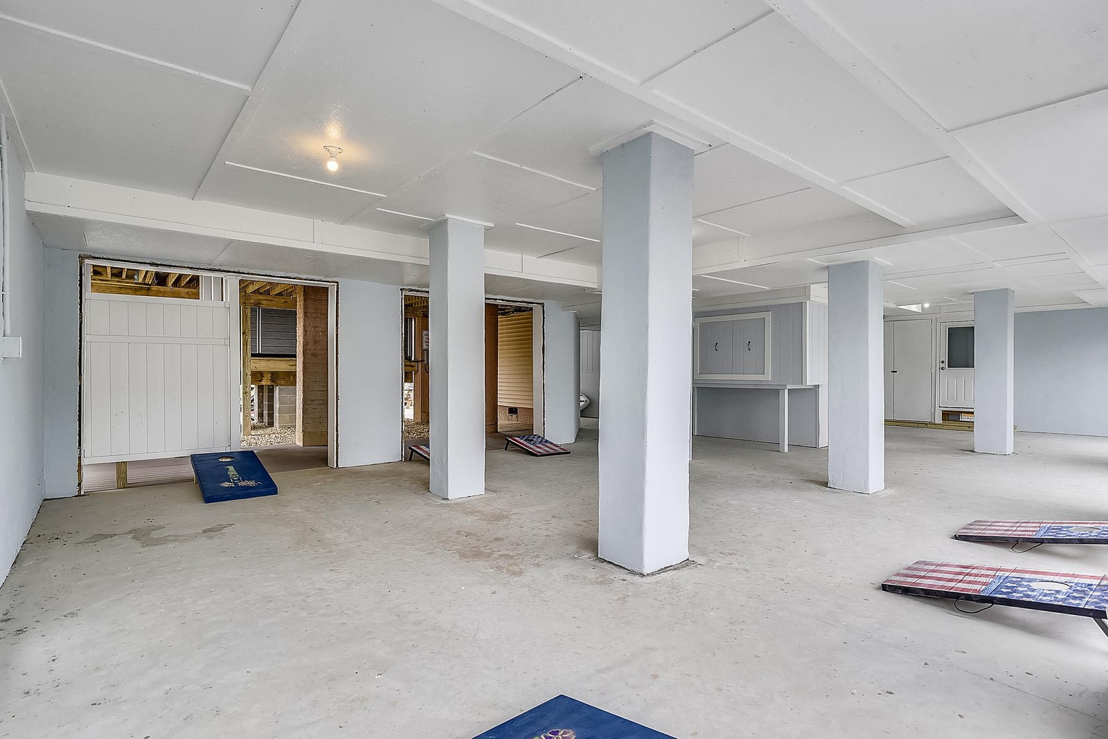 An open basement space currently under construction, offering a blank canvas for your vision. Fresh concrete floors and clean white columns create a bright, unfinished area awaiting your personal touch.