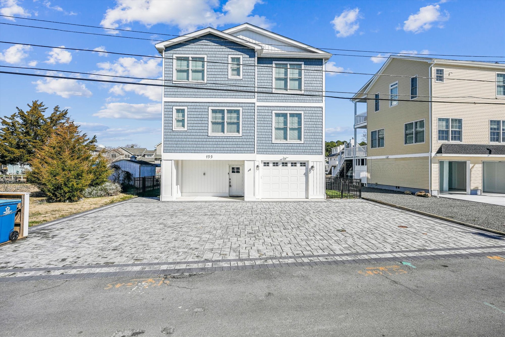 A well-maintained coastal property with modern gray siding stands ready for guests in a quiet residential neighborhood, featuring spacious parking and nearby beach access.