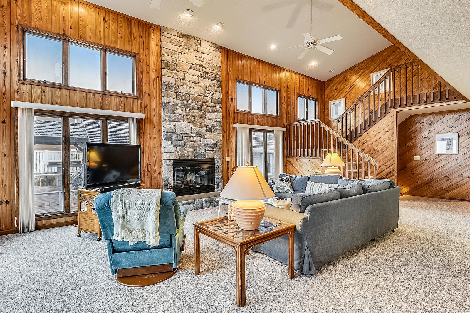 Unwind in this inviting open-plan living room with soaring ceilings, warm wood accents, and a cozy stone fireplace. Sink into plush seating and let your worries melt away.