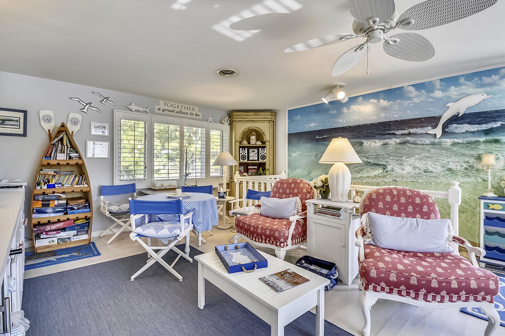 Unwind in your coastal-inspired living space where nautical charm meets comfort, complete with a vibrant ocean mural and cozy seating for your perfect beach getaway.