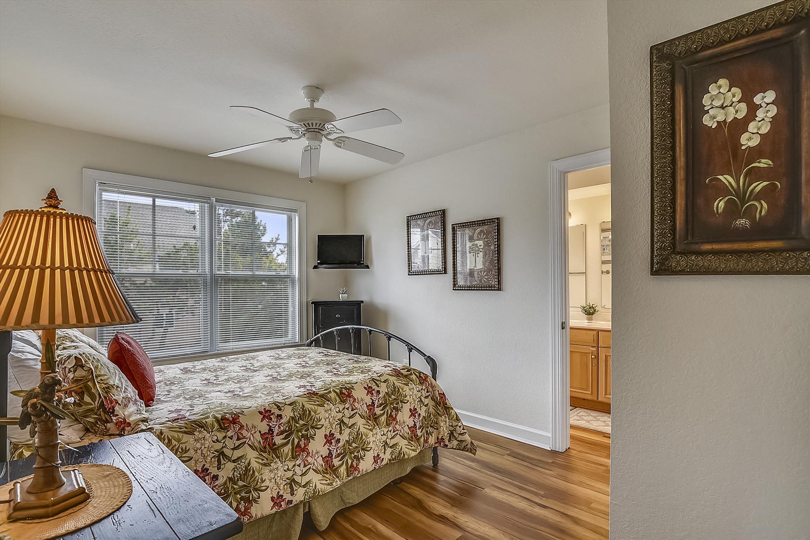 Your peaceful bedroom retreat features a plush bed with a ceiling fan, warm hardwood floors, and natural light streaming through large windows to ensure your comfort.