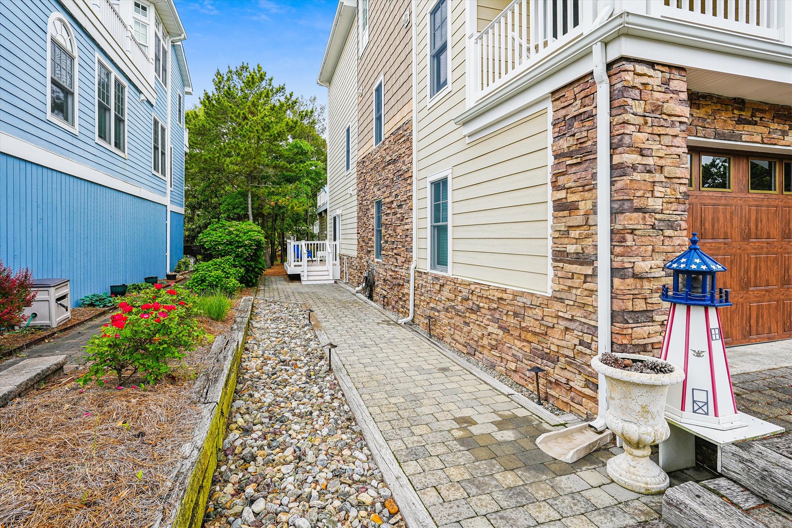 A charming coastal-inspired entrance pathway leads to your private retreat, bordered by vibrant gardens and a decorative lighthouse, welcoming you home in style.