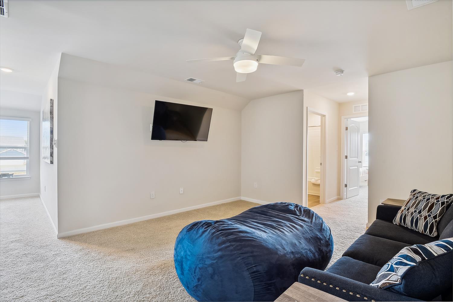 Unwind in your spacious loft with plush seating, wall-mounted TV, and gentle ceiling fan creating the perfect retreat.