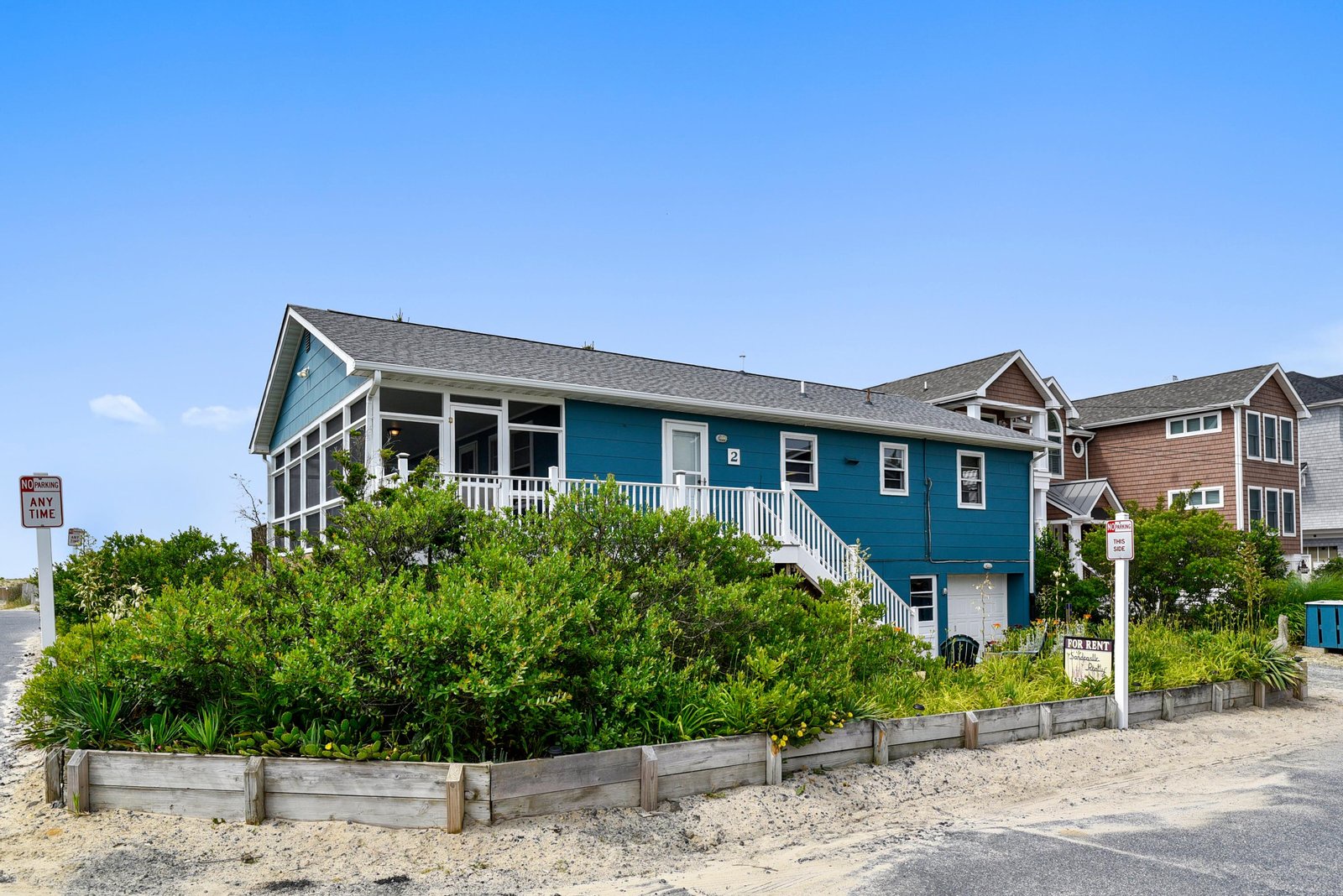 A charming beachside rental sits just steps from the sand, surrounded by natural coastal landscaping and located in a quiet neighborhood with easy beach access.