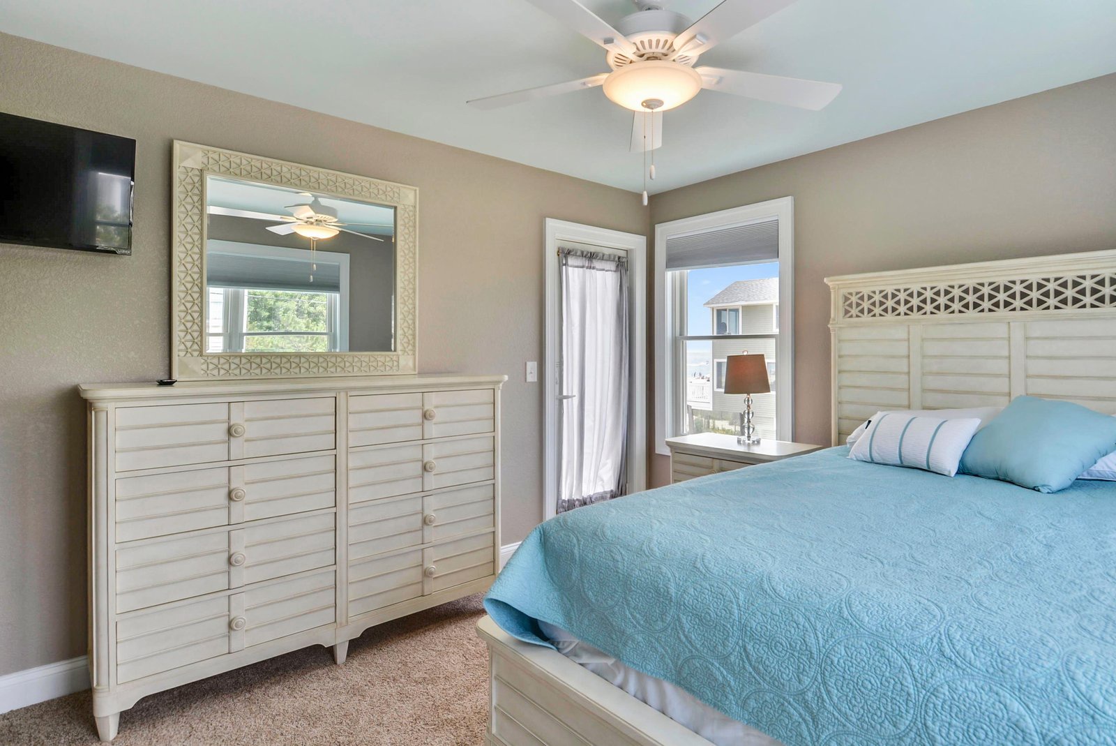 Your peaceful bedroom retreat features soft blue linens and coastal-inspired furnishings that invite restful sleep. Gentle breezes from the ceiling fan keep you comfortable all night long.