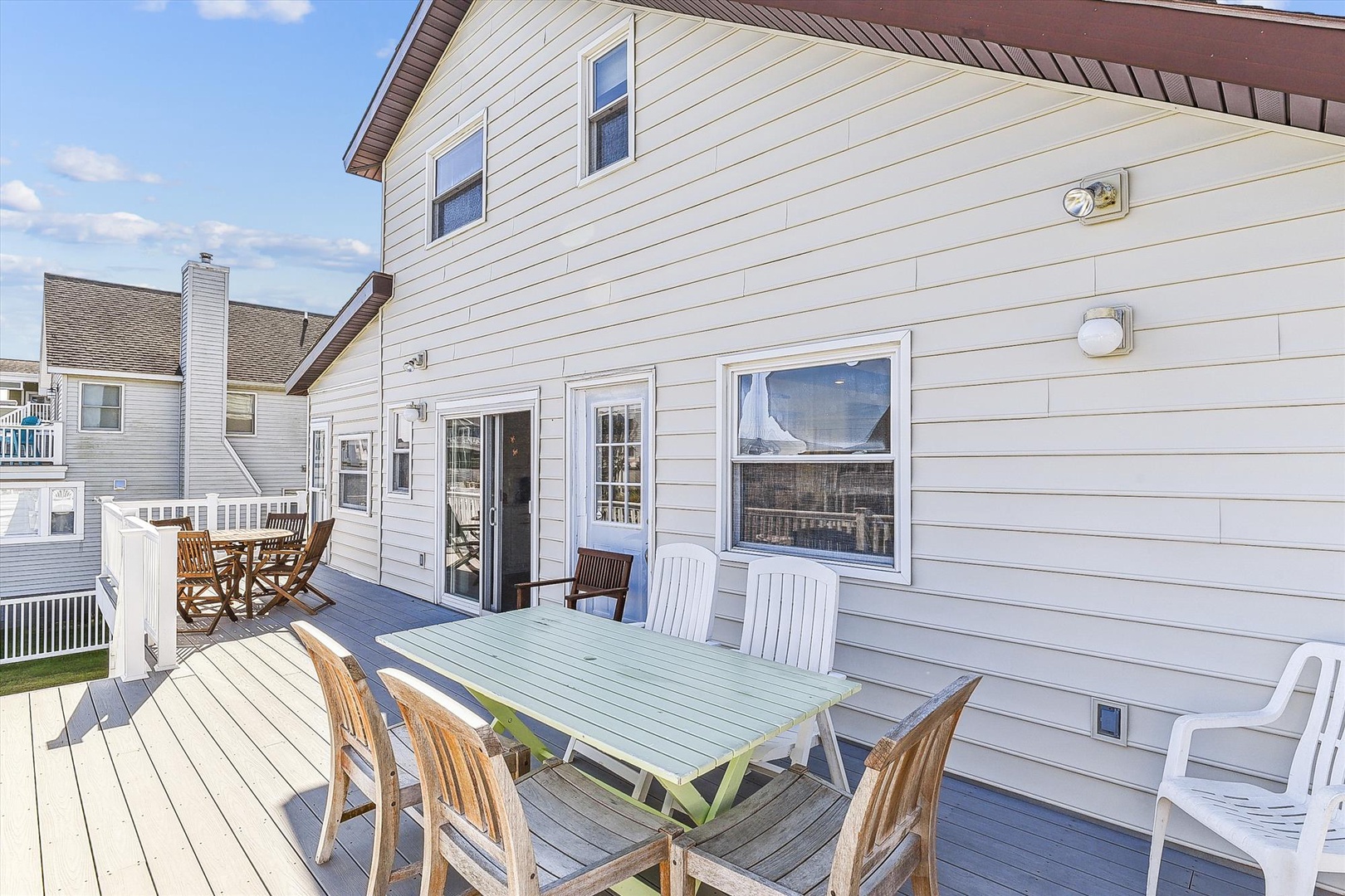 A spacious deck with outdoor dining welcomes your family gatherings under sunny skies, featuring casual seating and easy access to multiple entry points for seamless indoor-outdoor living.