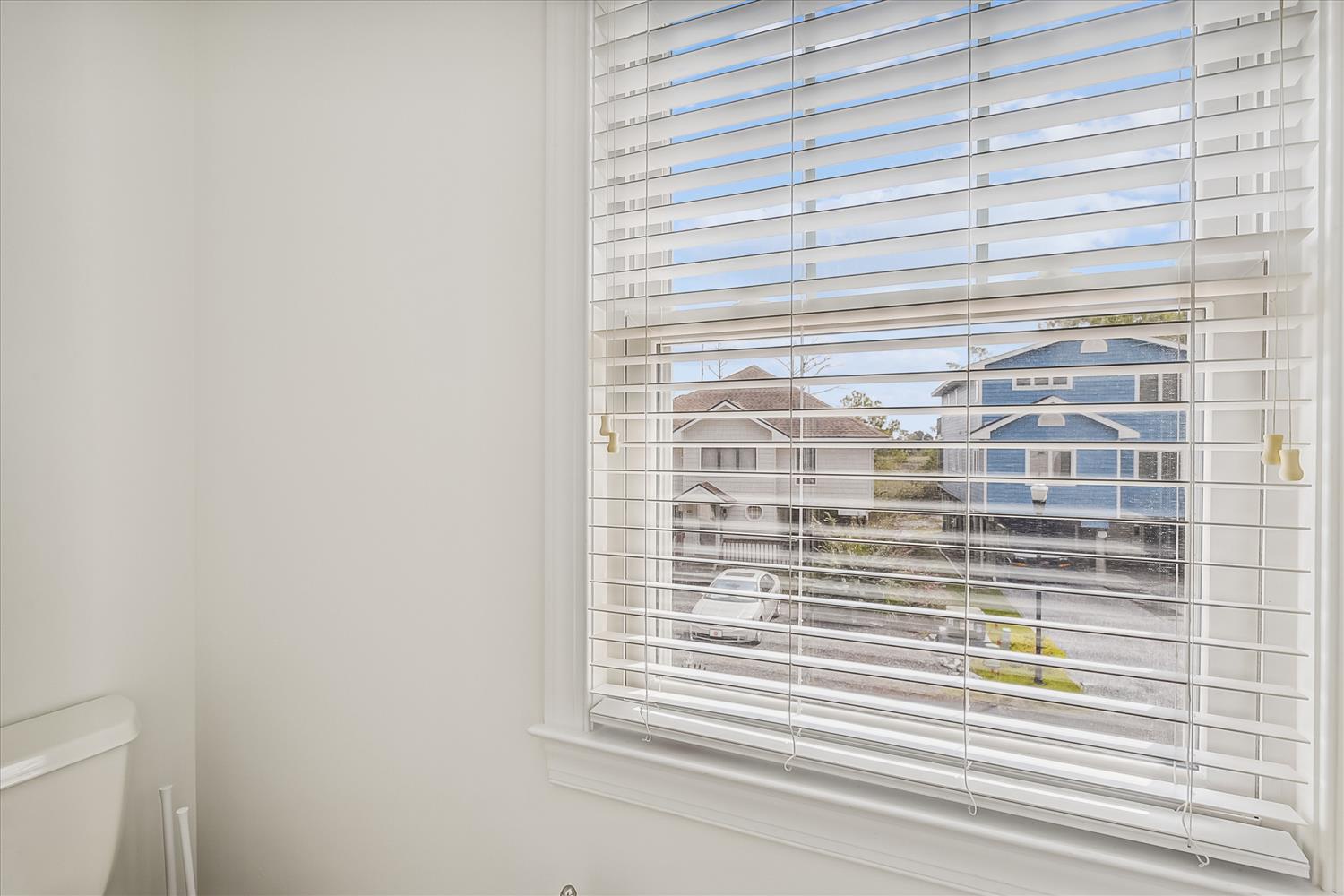 A bright window looks out over nearby homes and beach, flooding your bathroom with natural light and coastal breezes.