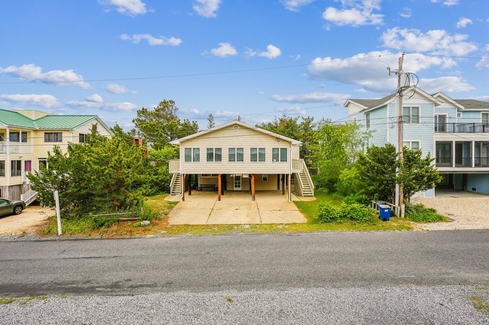 A welcoming beachside property situated in a peaceful coastal neighborhood, featuring convenient covered parking and easy beach access with neighboring vacation homes nearby.