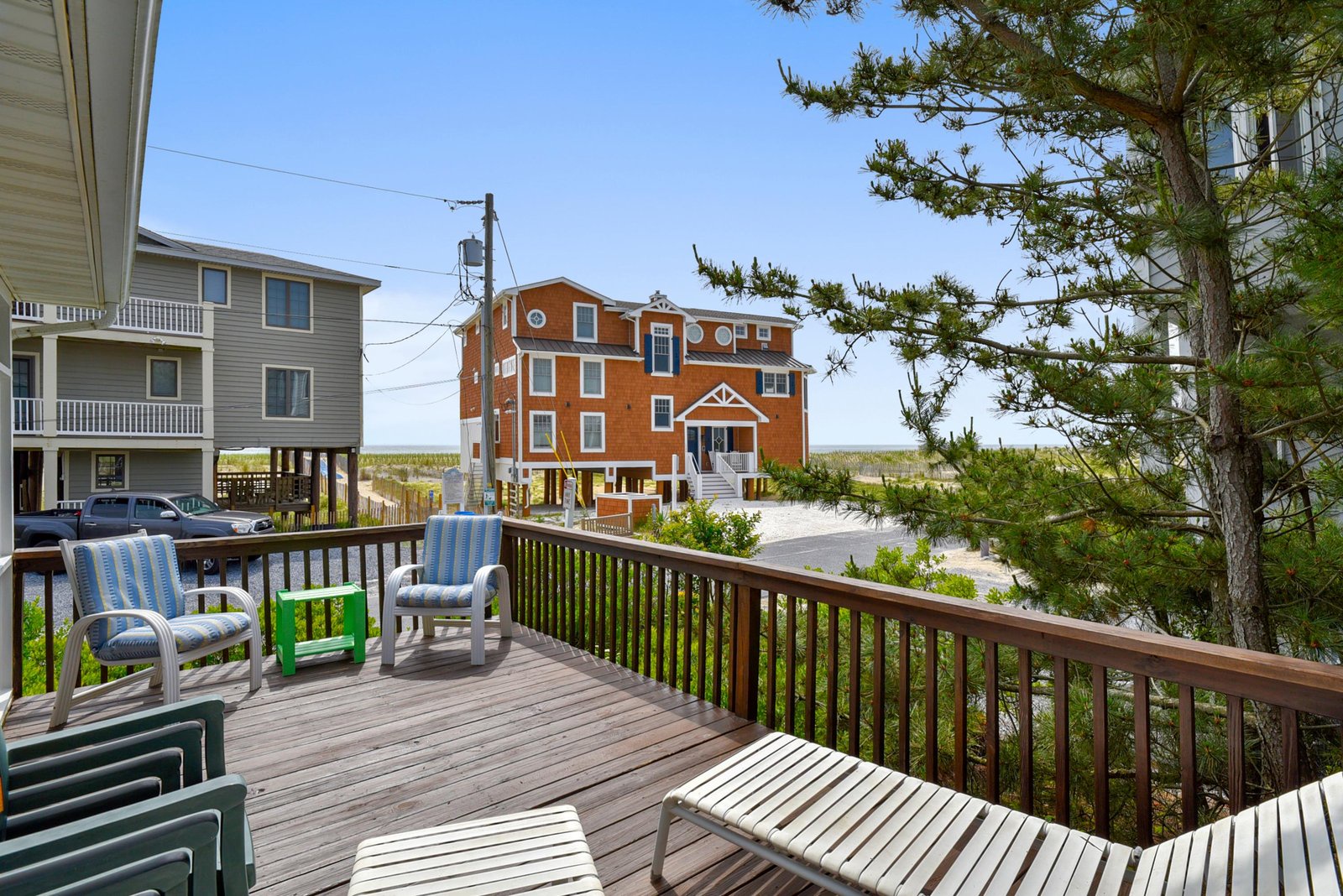 Relax on your private deck with comfortable seating and coastal breezes, overlooking neighboring beach homes and dunes—your perfect spot to unwind after a day by the ocean.