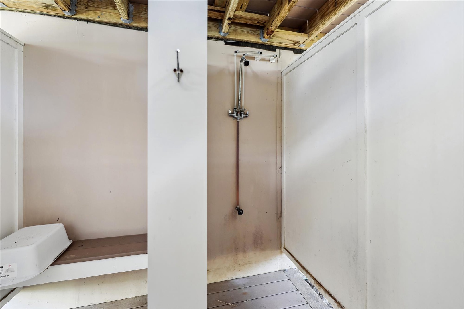 A simple walk-in shower with rustic exposed wood ceiling beams and minimalist design, providing your private space to refresh after a day of exploring.