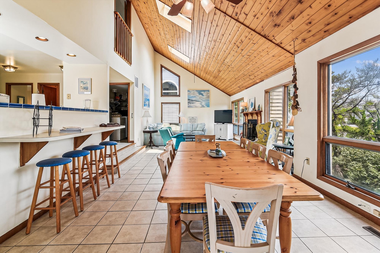 Step into this sun-drenched retreat where soaring wood ceilings and expansive windows invite the outdoors in. Gather at the farmhouse table or cozy seating area while natural light warms every corner of your peaceful escape.