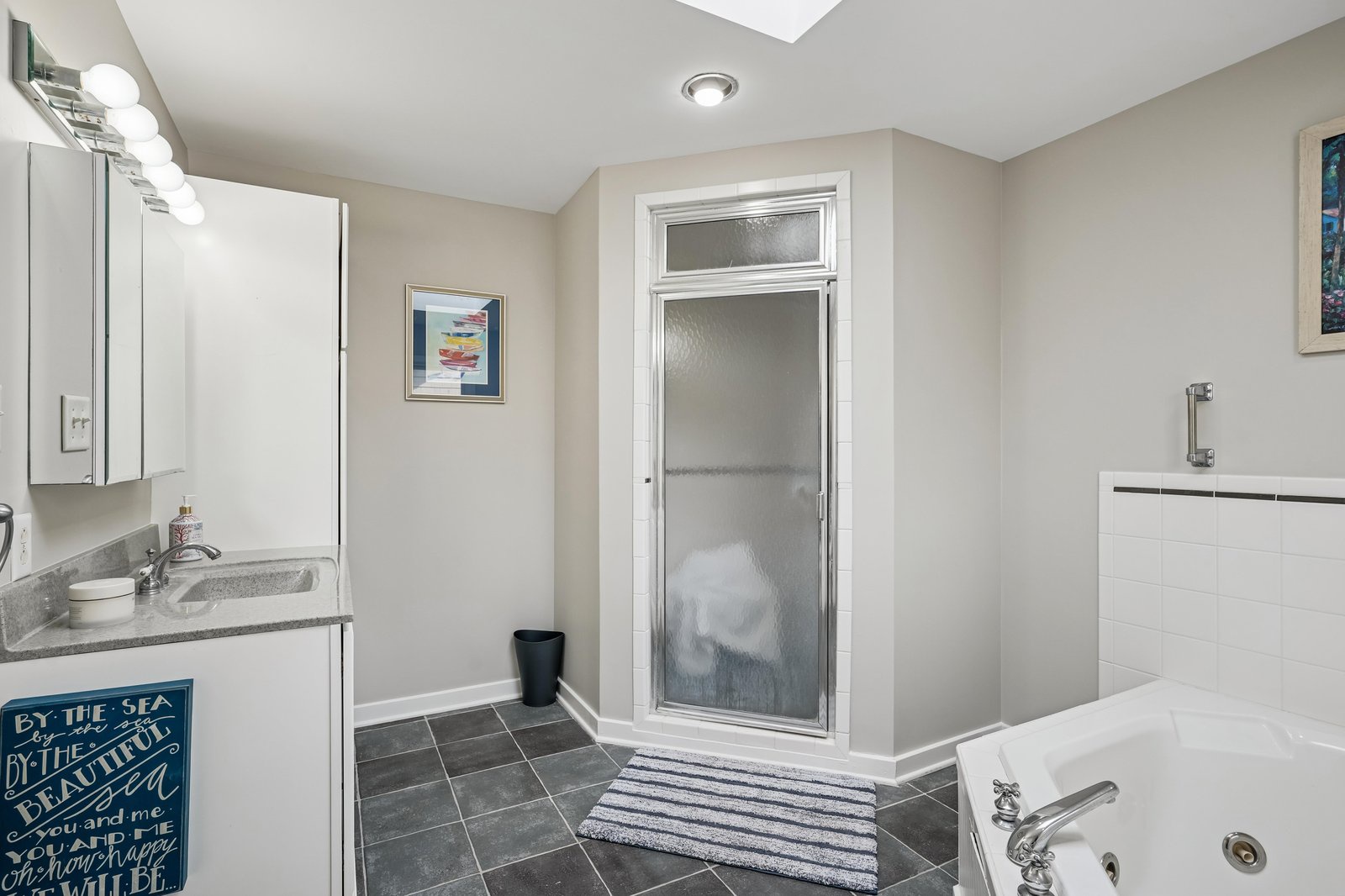 Step into your private bathroom with a skylight, featuring a soaking tub, walk-in shower, and plenty of natural light to brighten your morning routine.