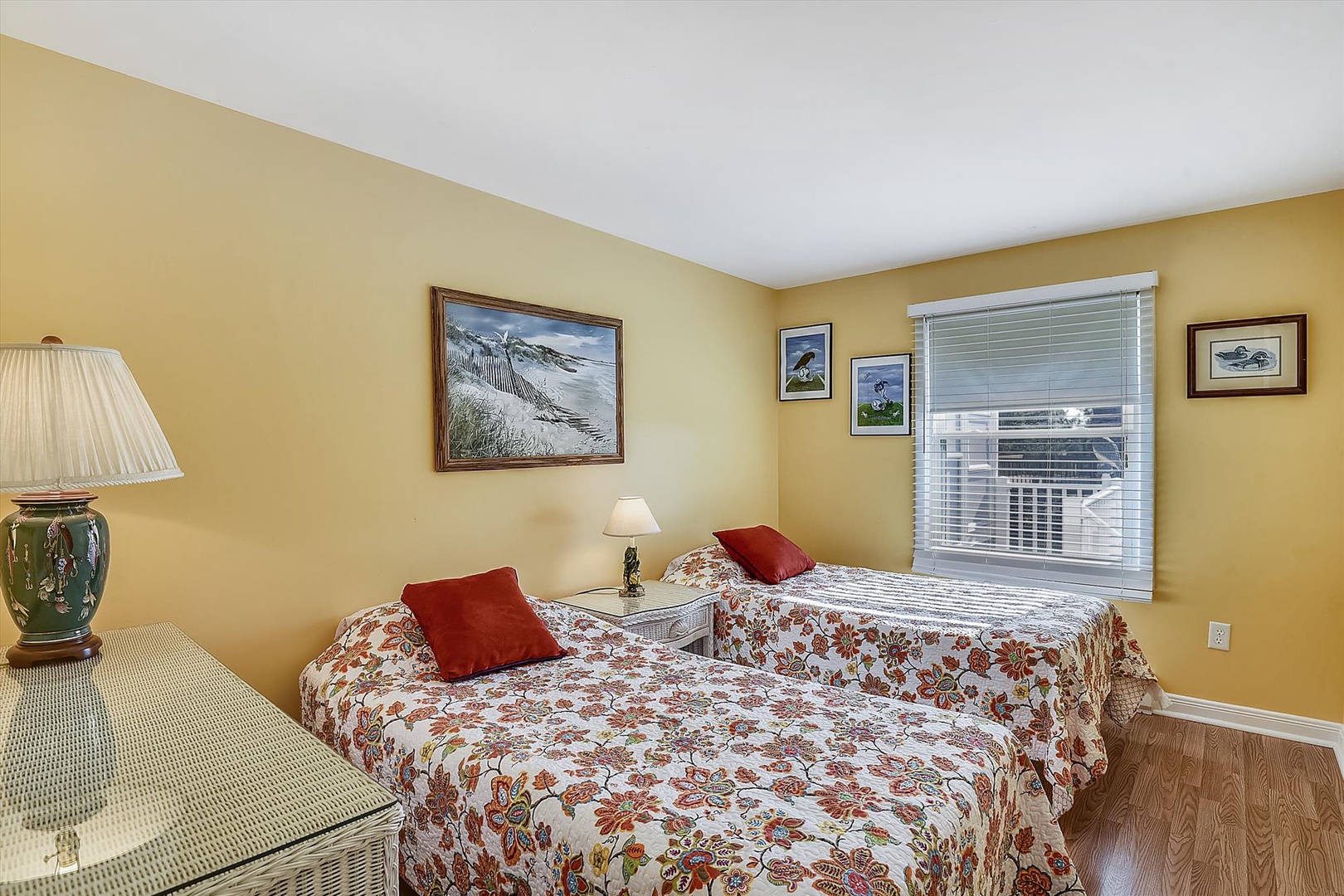 Your charming twin bedroom awaits, adorned with cheerful floral linens and warm golden walls. Cozy lamps and coastal artwork create a relaxing ambiance for restful nights.