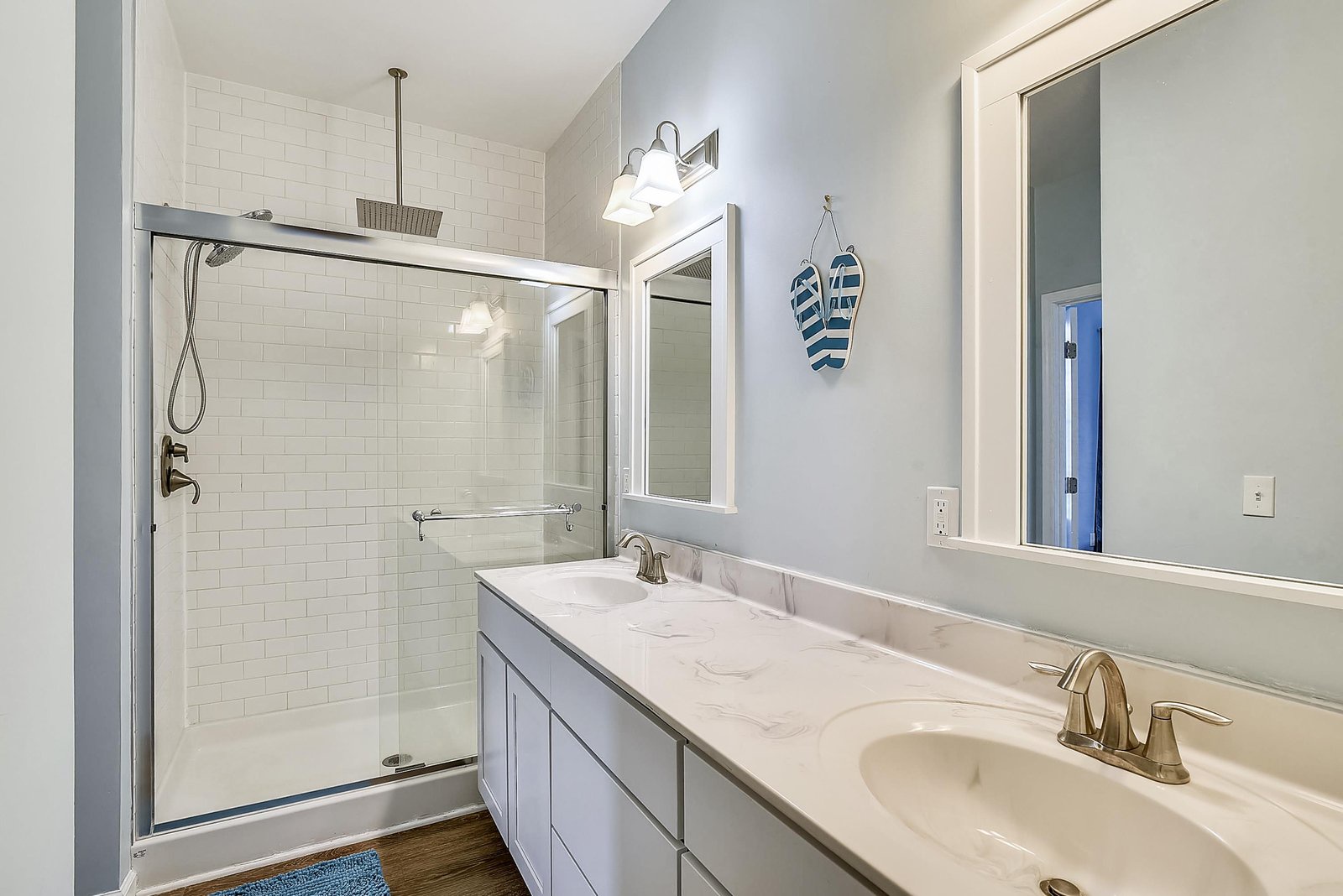 Refresh in your spacious, dual-sink bathroom featuring a glass-enclosed shower and crisp white tiles—perfect for unwinding after a day at the beach.
