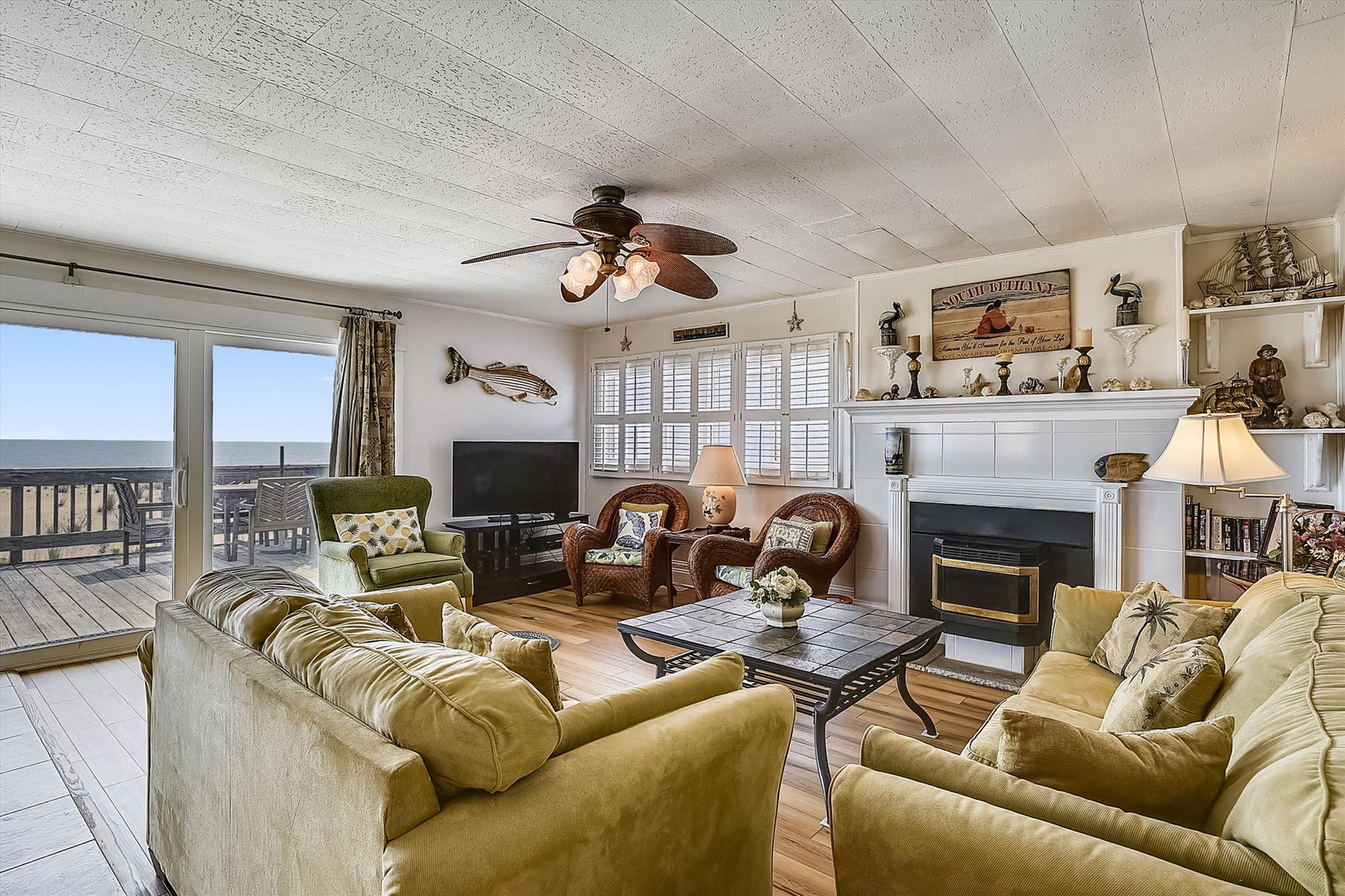 Sink into plush coastal seating while enjoying sweeping sea views through your private deck doors. Warm wood floors, nautical touches, and a cozy fireplace create your perfect beach retreat.