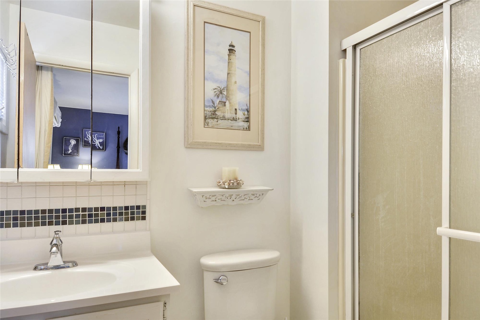 Step into your private bathroom, where coastal charm meets comfort with classic fixtures and a nautical-inspired lighthouse print to brighten your getaway mornings.