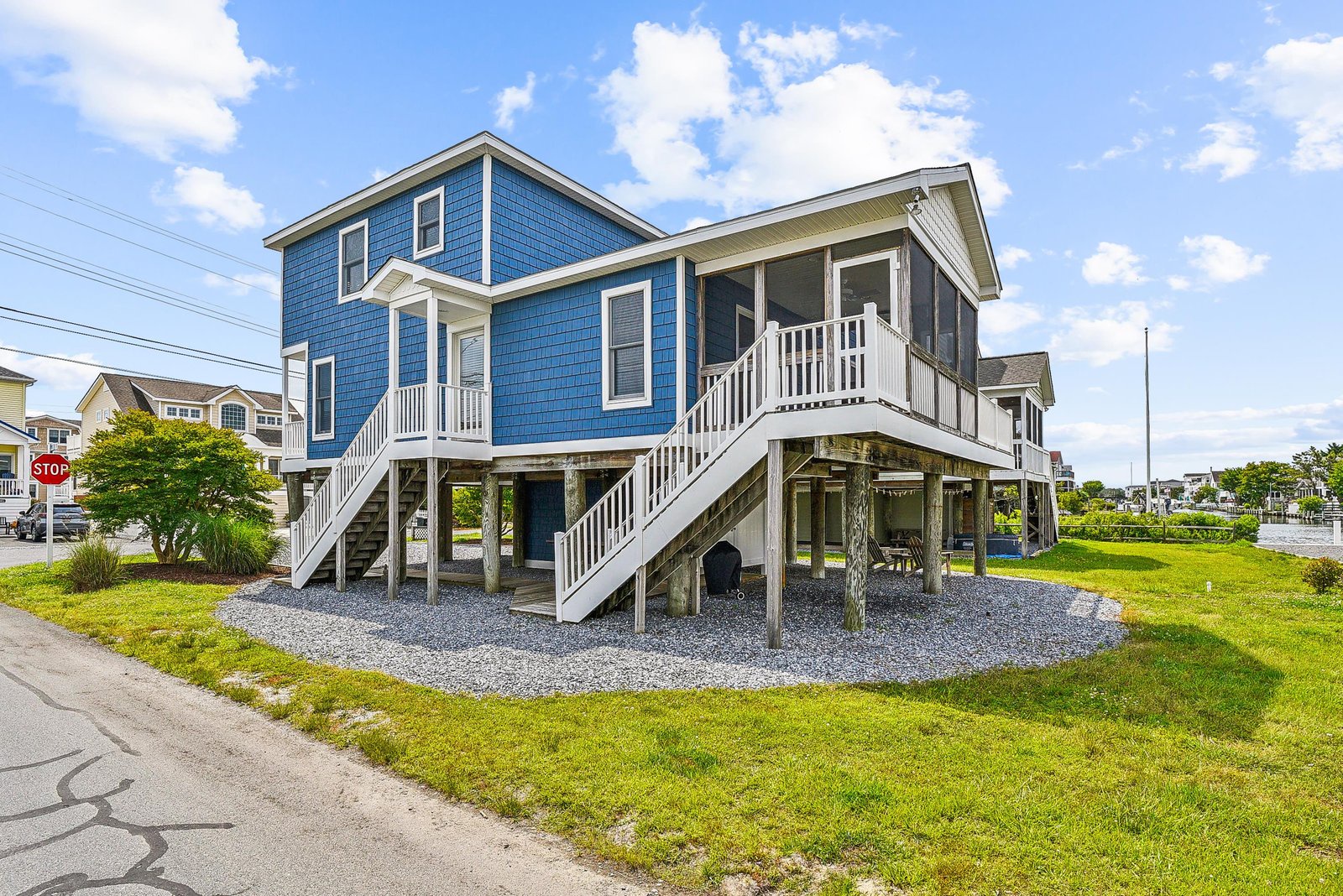 Charming coastal property with bright blue siding and an elevated covered porch, set in a quiet residential neighborhood just steps from the beach.