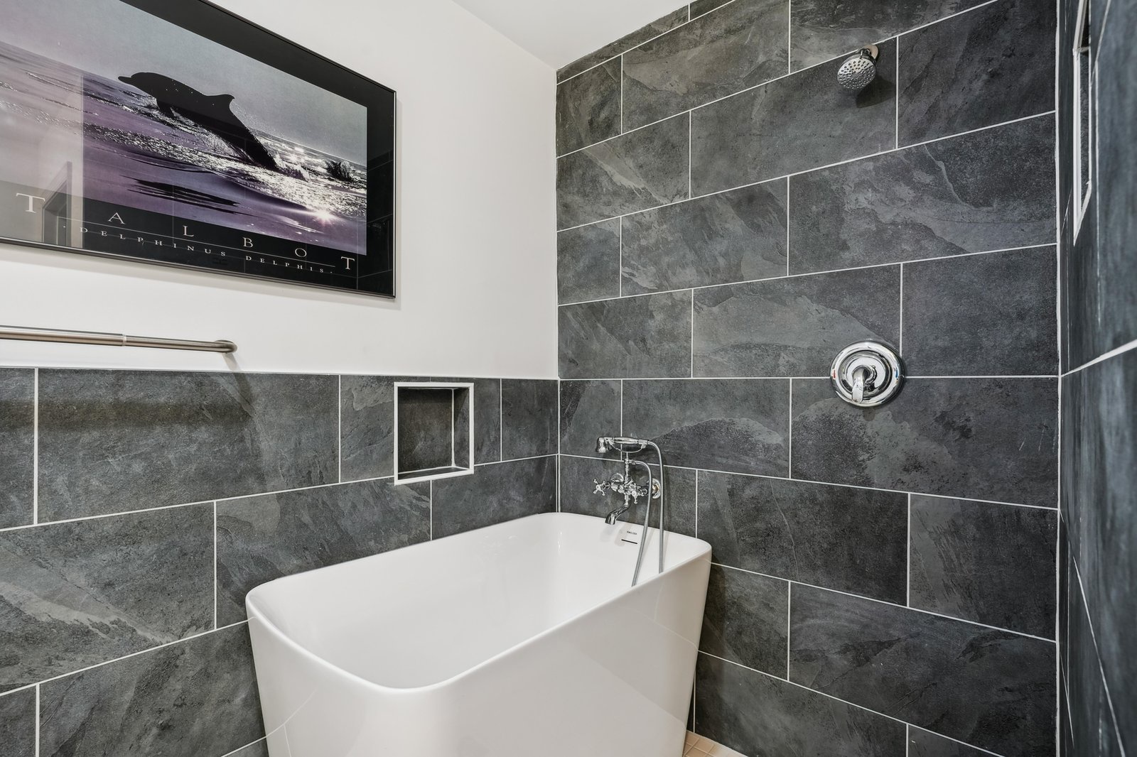 Unwind in your elegant bathroom with sleek gray tiling, a standalone soaking tub, and a refreshing walk-in shower designed for ultimate relaxation.