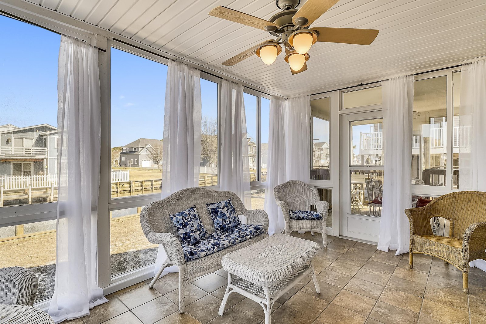 Relax in your private screened porch with breezy wicker seating and airy white curtains—a peaceful spot to enjoy your morning coffee or unwind after a day at the beach.