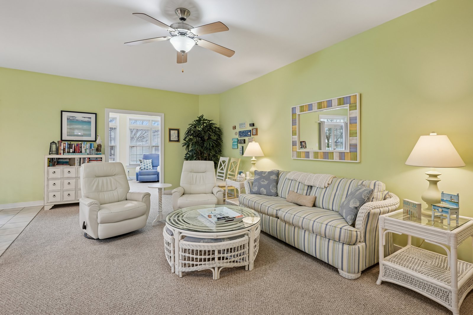 Relax in your bright, welcoming living room with comfortable seating and cheerful green walls that create a peaceful coastal retreat atmosphere.