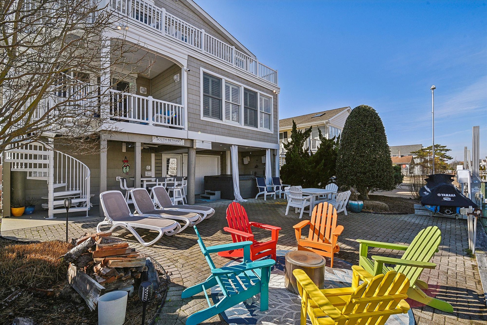 Bright Adirondack chairs invite you to relax in this cheerful waterfront patio space, perfect for morning coffee or sunset conversations.