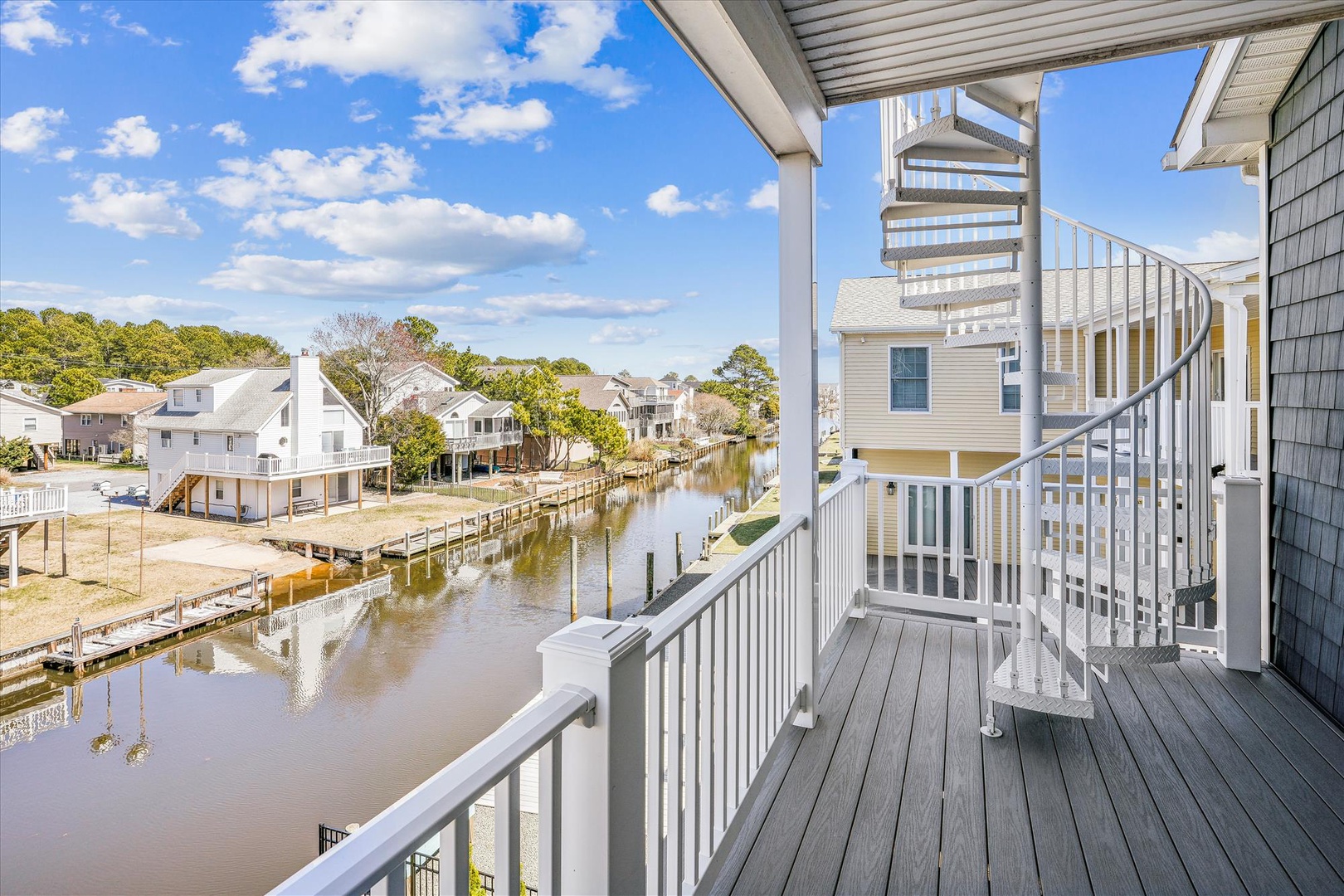 Waterfront balcony overlooking a peaceful canal lined with charming coastal homes and private docks—your morning coffee spot awaits.