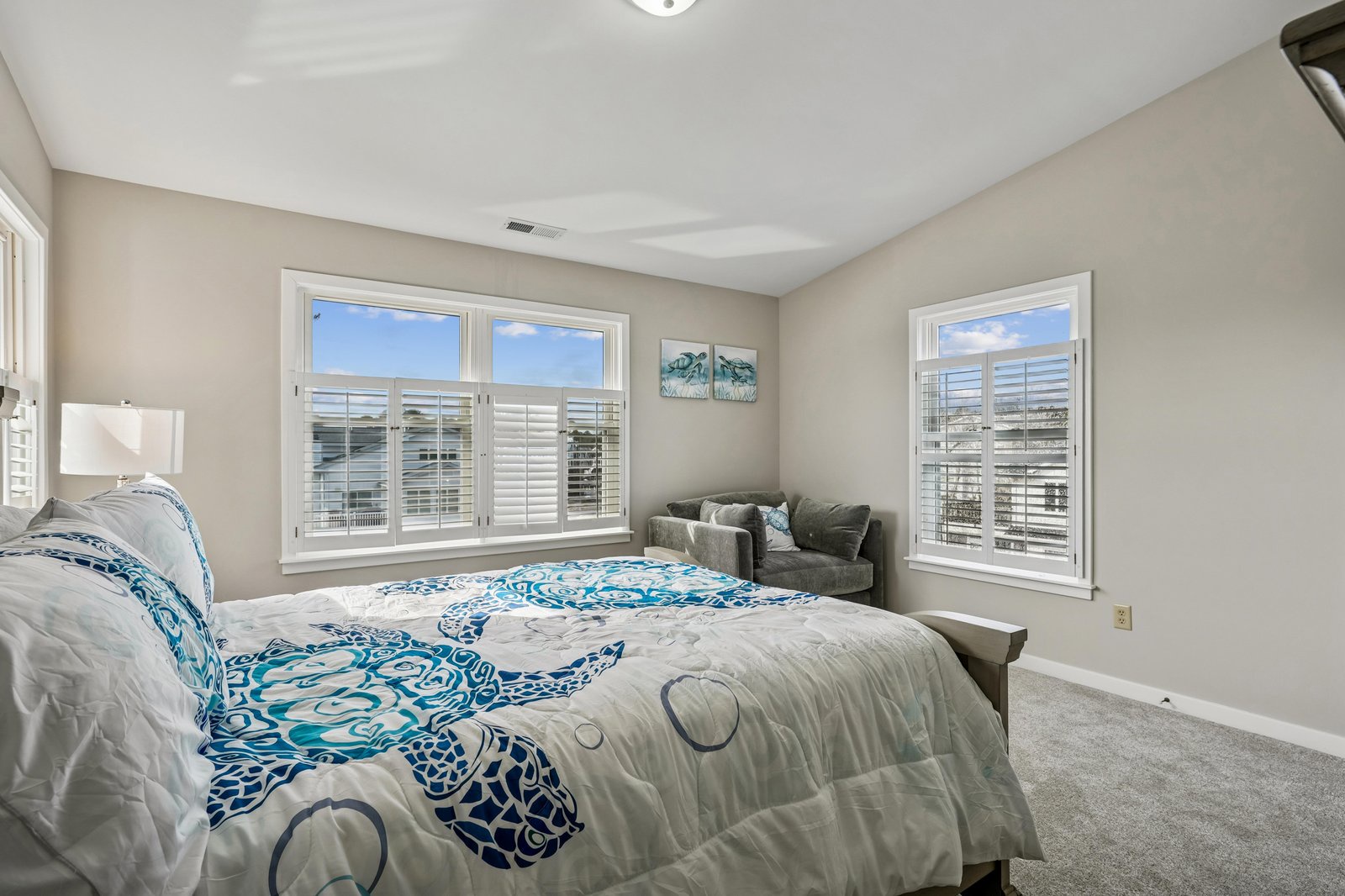 Drift off in this peaceful bedroom, where soft coastal hues and bright windows create your perfect retreat for restful mornings and serene evenings.