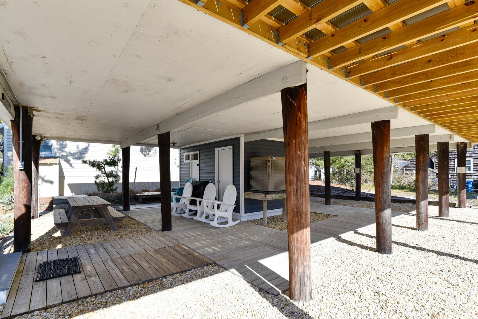 This covered outdoor area provides shade and comfort for your relaxation, featuring seating and a picnic table perfect for enjoying the coastal breeze.