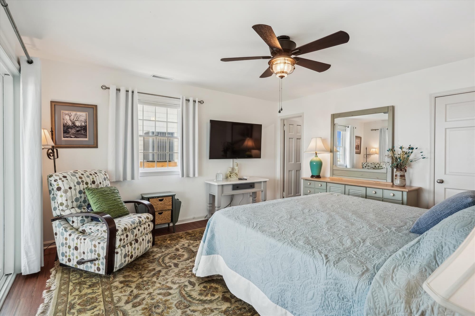 Drift off in your peaceful bedroom retreat featuring a plush bed, cozy reading chair, and entertainment at your fingertips. The ceiling fan ensures your perfect temperature for a restful night.