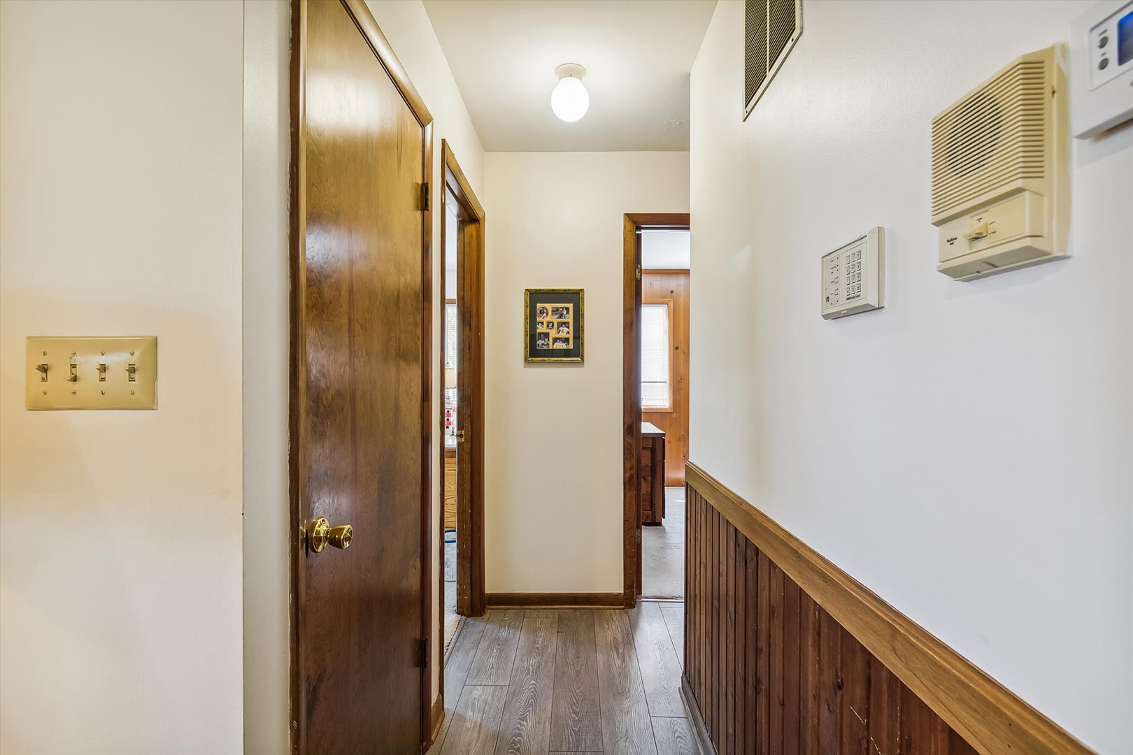 A warm hallway connects your private spaces, featuring classic wood finishes, climate control, and thoughtful touches like vintage-style light switches that add character to your comfortable retreat.